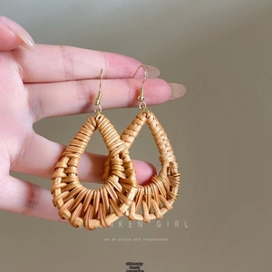 Detailed close-up of handmade fan-shaped raffia drop earrings with natural woven texture