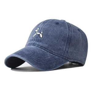 Detail view of white balloon dog embroidery on navy blue washed cotton baseball cap