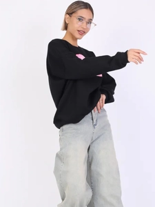 Seitenansicht des schwarzen Sweatshirts mit rosa Print und blauer Wide-Leg-Jeanshose