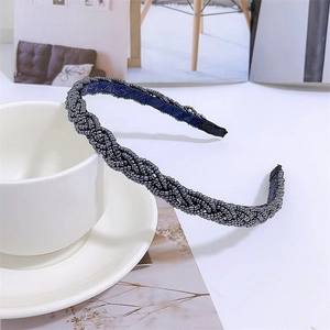 Detail of beaded braided headband in grey with navy lining next to a coffee cup