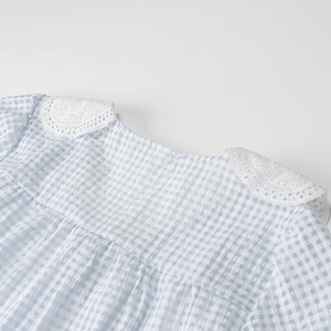 Detail view of blue and white plaid seersucker fabric with white lace collar