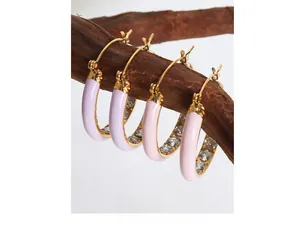 Close-up of gold hoop earrings with pastel enamel finish and sparkling zircon stones