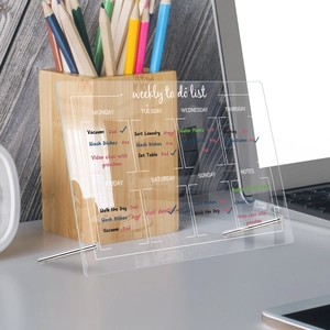 Clear acrylic weekly planner board on desk showing tasks and metal stands in detail