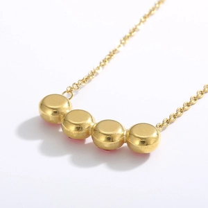 Elegante collana in acciaio al titanio dorato con cinque zirconi rossi su fondo bianco