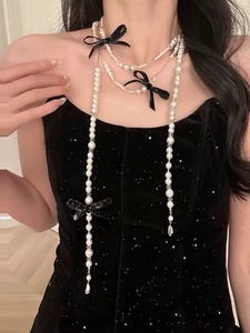 Detail of multi-layer pearl necklace with black bows on a velvet dress