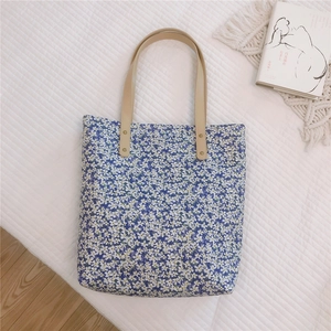 Detail showing the floral blue tote canvas with beige leather handles and gold rivets