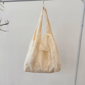 Detailed view of white floral lace embroidery texture on a canvas tote bag