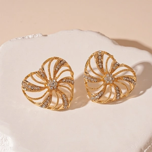 Macro shot of gold windmill heart earrings with white sparkling crystals on stone