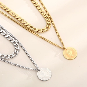 Detailed close-up of double-layered gold and silver coin necklaces with thick Cuban link chain