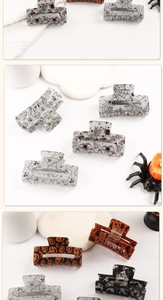 Close-up of Halloween hair claw clips with glittery spider web and ghost patterns
