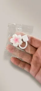 Close-up of white cherry blossom silicone straw topper in protective clear packaging