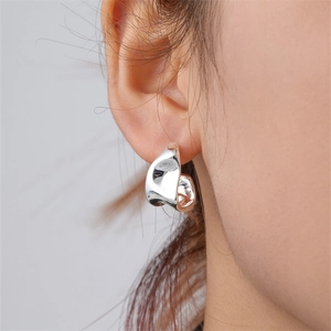 Close-up of minimalist silver irregular curved earrings worn by a model in a studio