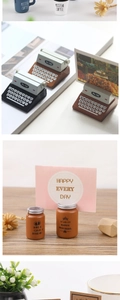 Detail of coffee cup and typewriter resin photo holders with metal clips on wood desk