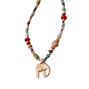 Bohemian beaded necklace featuring vintage elephant pendant and natural stones on white back