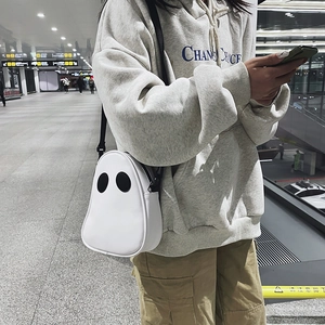 Side view of white ghost-shaped PU crossbody bag with black eyes and adjustable strap