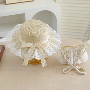 Close-up of summer straw sun hat and lace bag set with white bow on wooden surface