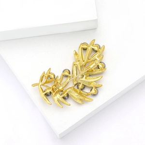 Detail view of a matte gold leaf brooch featuring dark grey faux pearls and secure pin