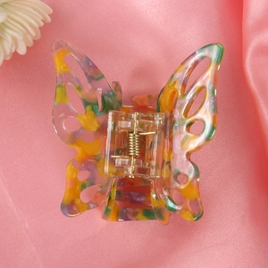 Close-up of butterfly claw clip with colorful marble pattern on pink silk fabric