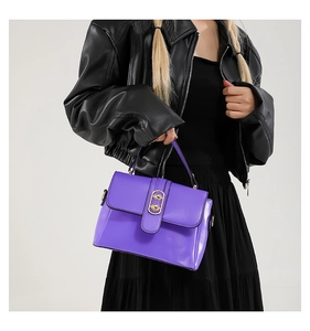 Detail of purple leather crossbody bag with golden double ring buckle on black outfit