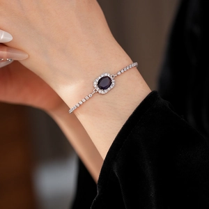 Detail of adjustable silver bracelet featuring an oval blue zircon with halo crystals