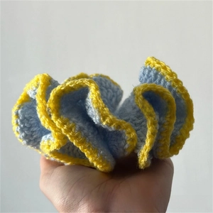 Detailed view of hand-crocheted ruffled hair scrunchie in blue and yellow knit design