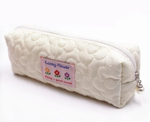 Close-up of quilted floral pencil case with lucky flower patch and pearl zipper puller