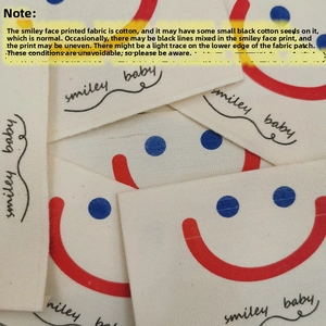 Detail of cotton sunshade curtain with red smiley face embroidery and smiley baby text