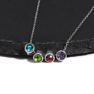 Gros plan sur collier argenté avec quatre pendentifs ronds en zircons colorés