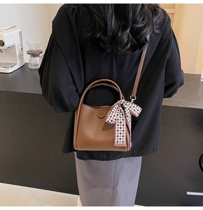 Brown lychee leather bucket bag with top handle and decorative plaid silk scarf accessory
