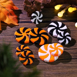 Halloween candy swirl resin beads in black, orange, and white on a dark wood background