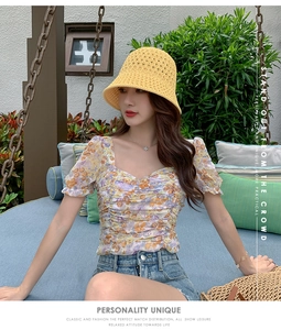 Portrait extérieur d'un mannequin portant un chapeau bob en tricot jaune et top fleuri