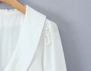 Detail of white women blouse with elegant oversized collar and pleated puff sleeves
