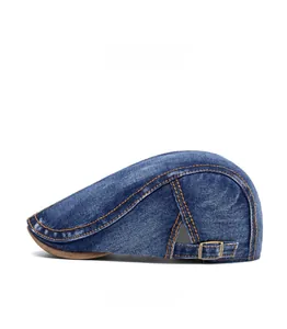 Detail view of washed navy denim flat cap with contrast orange stitching and metal buckle