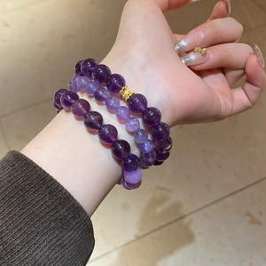 Detailed view of three layered amethyst beaded bracelets featuring a gold butterfly charm