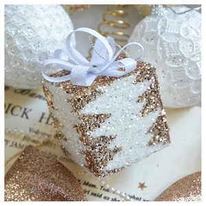 Macro shot of white and gold glitter Christmas gift box ornament with ribbon detail