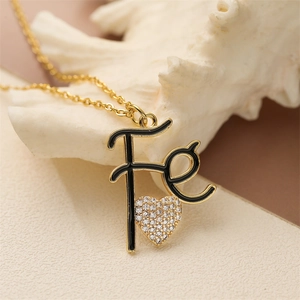 Close-up of gold plated Fe letter necklace with zircon heart on white coral
