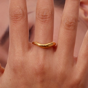 Close-up of a minimalist 18K gold plated stainless steel ring with an irregular wavy design
