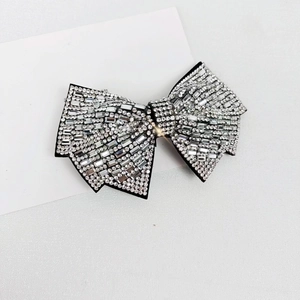Detailed close-up of a silver bow hair clip fully encrusted with sparkling white crystals