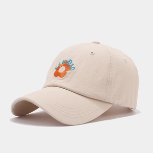 Close-up of orange flower and STUDIO embroidery on beige cotton baseball cap