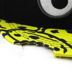 Macro shot of hip-hop cap brim showing unique bitten edge detail and yellow dot pattern