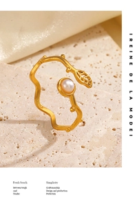 Macro view of gold leaf ring with a white pearl on minimalist wavy band detail