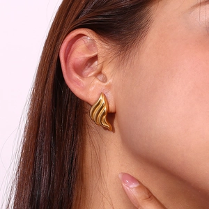 Close-up of gold plated liquid teardrop stud earring with a fluid striped texture