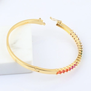 Polished 18k gold plated oval bangle featuring rainbow baguette cubic zirconia stones