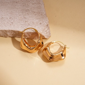 Vue détaillée des boucles d'oreilles créoles dorées avec texture métallique plissée