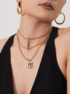 Close-up of layered 18k gold plated chains with square pendant and black enamel detail
