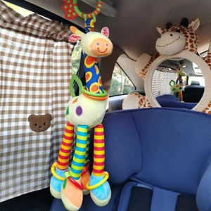 Plush giraffe stroller toy hanging inside car with sunshade curtains and car seat