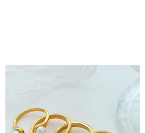 Detalle del anillo dorado ajustable con pequeñas perlas blancas y diseño abierto
