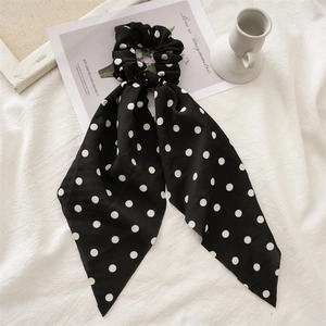 Detailed view of black polka dot fabric scrunchie with long streamers on flat lay