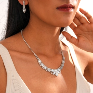 Close-up of diamond-encrusted silver oval drop necklace and earrings set on model