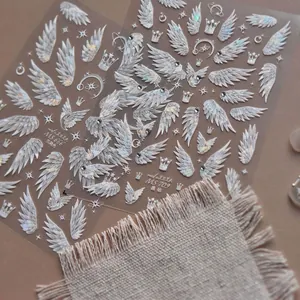 Detailed 3D nail art stickers featuring angel wings, crowns and sparkling crystals